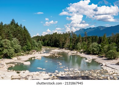 River Gail flowing through the Schuett in the natural park Dobratsch in Villach, Carinthia, Austria. Gailtaler and Villacher Alps. Riverbank is full of massive rocks. View on Dreilaendereck