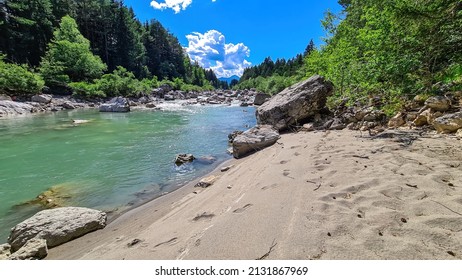 The river Gail flowing through the Schuett in the natural park Dobratsch in Villach, Carinthia, Austria. Gailtaler and Villacher Alps. The riverbank is used as a beach. Swimming in crystal clear water