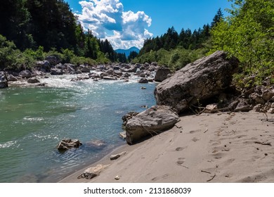 The river Gail flowing through the Schuett in the natural park Dobratsch in Villach, Carinthia, Austria. Gailtaler and Villacher Alps. The riverbank is used as a beach. Swimming in crystal clear water