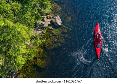 Vista aérea del río Kayaker. Deportista caucásico en el Paddling de Red Kayak en el río escénico a lo largo de la costa.