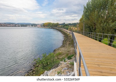 River lake water pier wooden catwalk bank way path cycling track urban park city horizon background