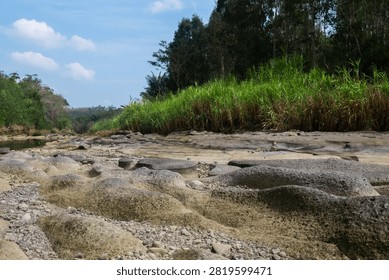 River with a limestone bed is flowing through the landscape. The river has dried up due to the dry season, which has led to a decrease in water levels and a change in the river's natural flow.