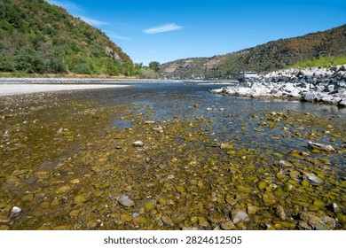 River with low water level, upper middle rhine valley near Kaub, Germany, dry riverbed due to extreme drought in Europe, impact freight transport and hinder shipping