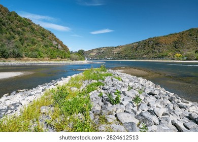 River with low water level, upper middle rhine valley near Kaub, Germany, dry riverbed due to extreme drought in Europe, impact freight transport and hinder shipping