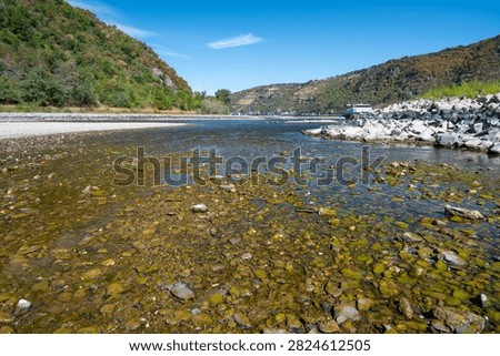 River with low water level, upper middle rhine valley near Kaub, Germany, dry riverbed due to extreme drought in Europe, impact freight transport and hinder shipping