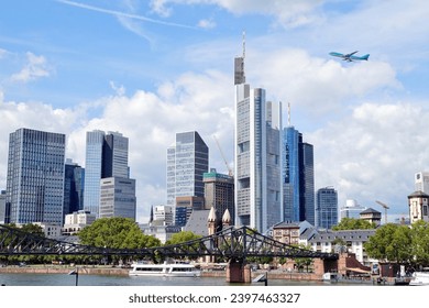 River - Main with european city skyline. Airliner is flying, Jet plane in high flight. Skyscraper buildings in Germany on blue sky background. Business and Financial Center Frankfurt Main. Travel  - Powered by Shutterstock