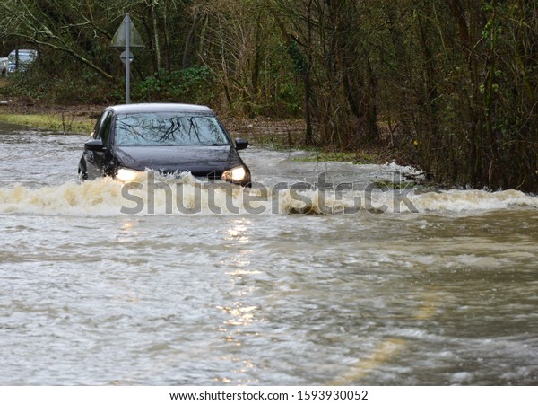 The river Mole\
has flooded its banks, cars are trying to drive through the flood\
waters on December 20th \
2019