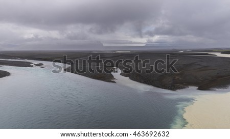 River Nupsvotn with large lava sand fields near Kalfafell with dark clouds on Iceland.