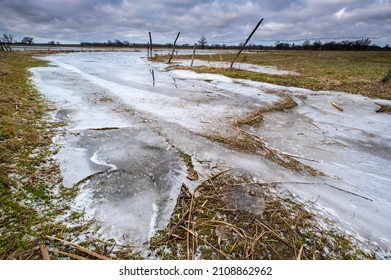 River Partially Frozen In Winter, Sunset, Road Flooded With Water And Frozen