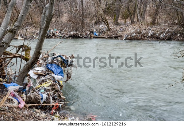 River pollution. Plastic bags, bottles, garbage\
and trash dumped in the river in nature. Rubbish and waste floating\
in contaminated lake. Ecological and environmental disaster.\
Ecology issue. Garbage.