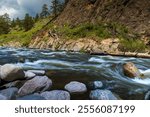 River rapids on the Big Thompson River of Colorado.  Snow melt from the Rocky Mountains rushes downstream towards the Front Range. Rocks, boulders, canyon views and whitewater. Dark storm clouds.