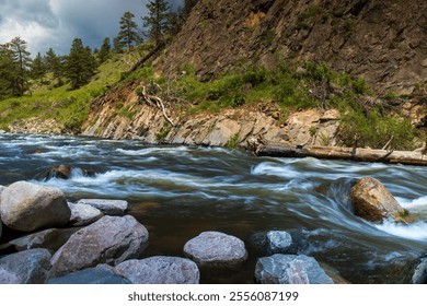 River rapids on the Big Thompson River of Colorado.  Snow melt from the Rocky Mountains rushes downstream towards the Front Range. Rocks, boulders, canyon views and whitewater. Dark storm clouds. - Powered by Shutterstock