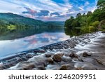 The River Rothay flowing over the weir at Grasmere Lake towards Rydal and on to Windermere in the Lake District National Park. A lovely morning sky over the Barrowdale fells in the distance.