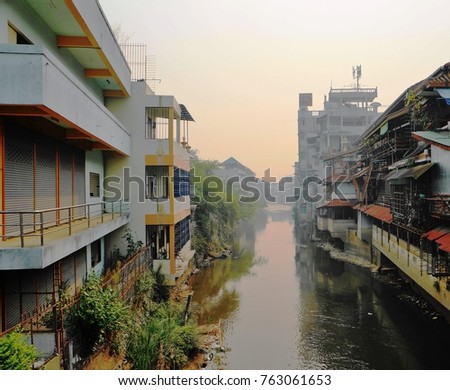 A river running through between buildings in the town of Tachileik, in the Republic of Myanmar (Burma).
