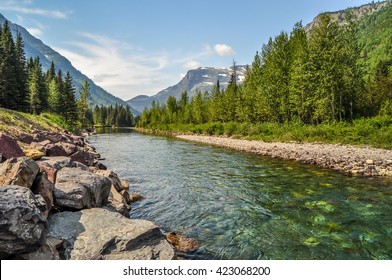 A river runs down from the mountains that guard a valley in Glacier National Park, Montana.