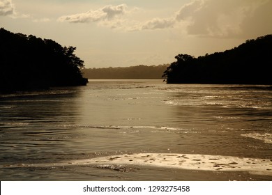 River Shoreline Silhouette Seen From The Middle Of A River As You Are About To Pass Between Two Peninsulas.  With A Vintage Effect.