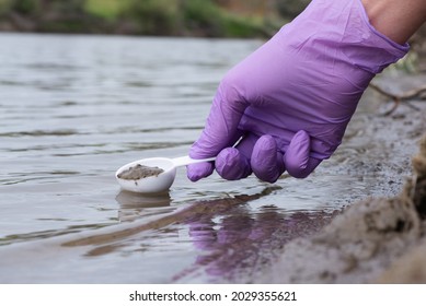 River soil composition concept. Woman a scientist takes a sludge sample from a river close up.