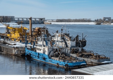 River transport, equipment, tugs, dredger, crane at the pier during the onset of spring. Industrial landscape.