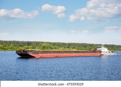 River Tugboat Moves Cargo Barge On The Volga River In The Summer Navigation