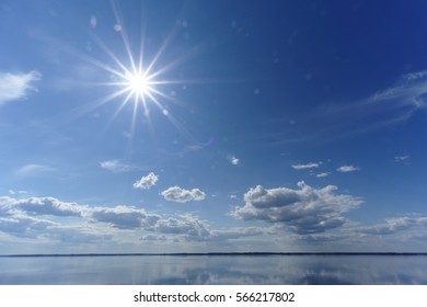 River view with clouds reflected in it, the sun in the frame, Volga, Russia.