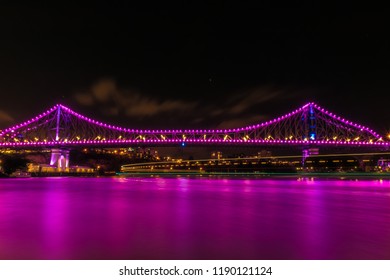 River water of magenta color flowing under modern illuminated bridge at dark night in Brisbane, Australia - Shutterstock ID 1190121124
