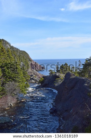river and waterfall landscape with view towards the Atlantic ocean along he East Coast trail, Stiles Cove Path near Flatrock Newfoundland Canada; early Spring 