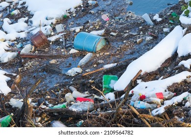 A River In Winter, Water And Snow Spoiled With Human Waste, Made Of Plastic And Gas Bottles, Poisoning Environment