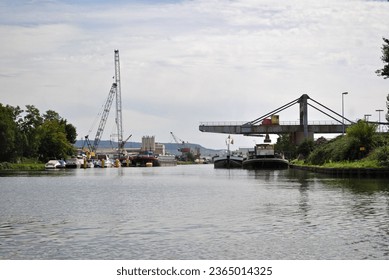 Riverside Industrial Loading Cranes Reflected in Calm Waters of River on Sunny Day 