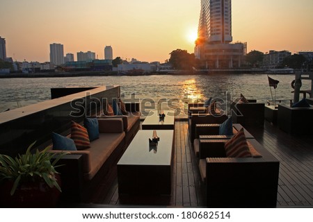riverside restaurant seats and tables near Chao phraya river during sunset in Bangkok, Thailand