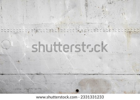 Riveted with button-head rivets metal plate (side of a sea vessel) painted in white as an industrial background