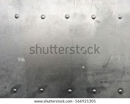 Riveted metal background, detail metal textured background from aircraft. Old grunge metal fragment of protective structure made of metal plates sheets assembled with button head rivets.
