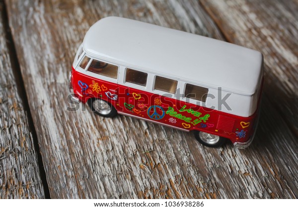 RIVNE, UKRAINE - MARCH 01, 2018:  Small\
red hippie bus toy Miniature VW Bulli 1962 is standing on wooden\
background on MARCH 01, 2018 in RIVNE,\
UKRAINE