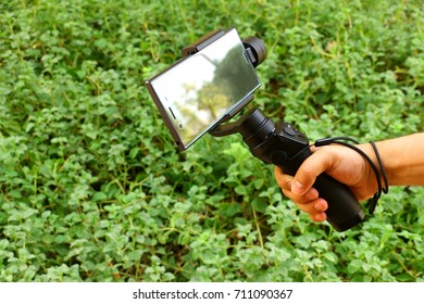 Riyadh, Saudi Arabia - September 8, 2017: A Hand Holds A DJI Osmo Mobile Gimbal With A Smartphone To Stabilize Video Clips Or Footages Or To Take Automatic Panorama And Selfie Photos By A Click