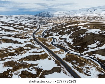 Road 73 creating a path through winter snow covering rough terrain and distant mountains