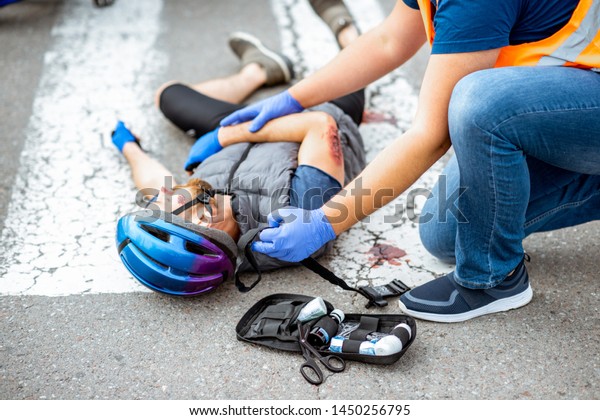 Road\
accident with injured cyclist lying on the pedestrian crossing near\
the bicycle and car, male driver providing first\
aid