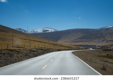 Road along with autumn landscape of vast plains in  China. Breathtaking, amazing, endless desert mountain. Mount Everest of Tibet, dry and cold mineral landscape and winding gravel road . Blue sky.