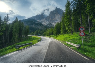 Road in alpine mountains at sunset in summer. Dolomites, Italy. Beautiful road, green tress, high rocks in clouds. Landscape with empty highway through the mountain pass in summer. Travel. Transport - Powered by Shutterstock