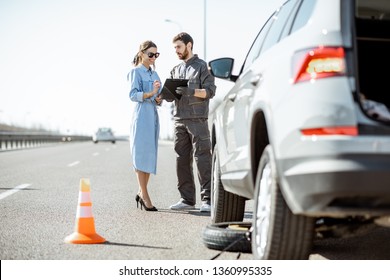 Road Assistance Worker Signing Some Documents With Woman Near The Broken Car On The Highway