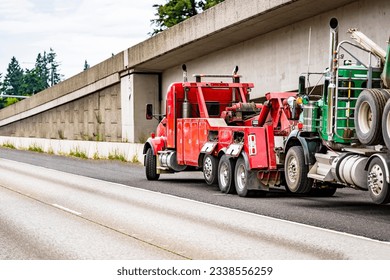 Road assistant helper mobile heavy duty big rig towing semi truck pick up the broken out of service green big rig semi truck tractor with engine damage standing on the highway road shoulder
