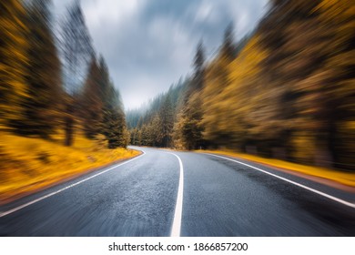 Road In Autumn Foggy Forest In Rainy Day With Motion Blur Effect. Beautiful Mountain Roadway And Blurred Background With Orange Trees In Fog. Empty Asphalt Road Through Woodland In Speed Motion. Fall