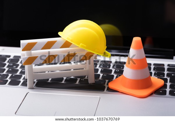 Road Barrier With Hard Hat And Traffic Cone On Laptop Keypad