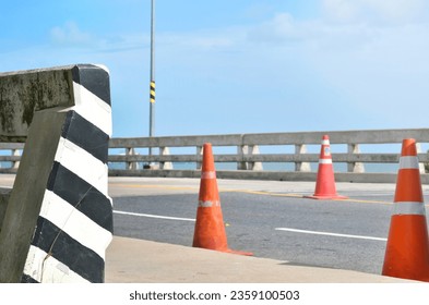 Road barrier with orange traffic cones On the bridge over the road, the background is a clear sky and soft sunlight,Sea bridge, traffic signs, transportation. - Powered by Shutterstock