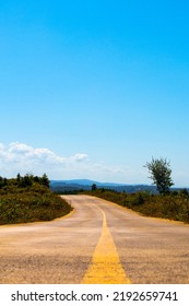 Road Between Forest And Countryside. Way View From Ground Level. Blue And Cloudy Sky. New Hopes And The Door To The Future. Cinematic Photography. Road Trip Idea Concept. No People, Nobody.