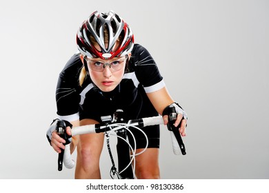 Road Bicycle Woman Riding Her Bike And Concentrating On Winning The Cycle Race. Full Cycle Gear And Action As A Real Cyclist Trains For Fitness. Isolated On Grey.