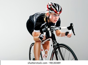 Road Bicycle Woman Riding Her Bike And Concentrating On Winning The Cycle Race. Full Cycle Gear And Action As A Real Cyclist Trains For Fitness. Isolated On Grey.