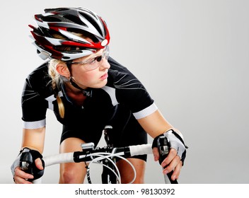 Road Bicycle Woman Riding Her Bike And Concentrating On Winning The Cycle Race. Full Cycle Gear And Action As A Real Cyclist Trains For Fitness. Isolated On Grey.