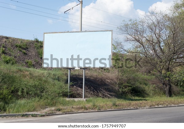 road billboard, against the\
background of green trees of the road, an empty ad-free billboard\
along the road. Advertising, signboard, blank, pattern, copy\
space