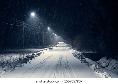 Road In The Blizzard Snow In Winter At Night. In The Light Of Lamps Visible Falling Snow.