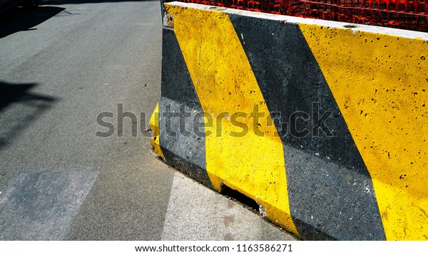 road bollards in yellow and black striped concrete,
in the sun