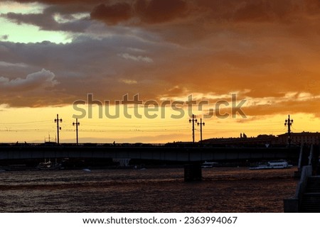 Road bridge over the river with beautiful street lamps at sunset. Evening city.